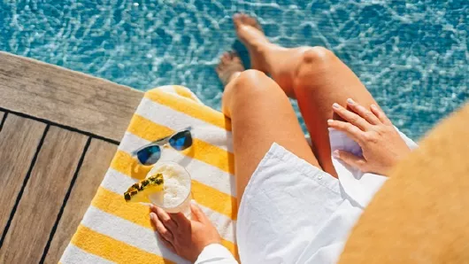 Frau am Pool mit Sonnenbrille und Handtuch Frau am Pool mit Sonnenbrille und Handtuch